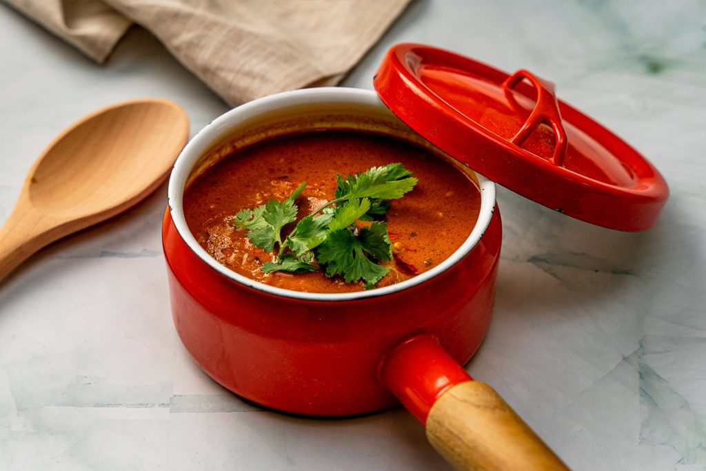 Kalaonni Curry masala -keittoannos punaisessa kattilassa.