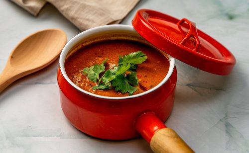 Kalaonni Curry masala -keittoannos punaisessa kattilassa.